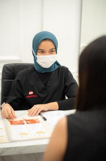 Seorang dokter mendengarkan dengan penuh perhatian saat berkonsultasi dengan klien di klinik Immoderma